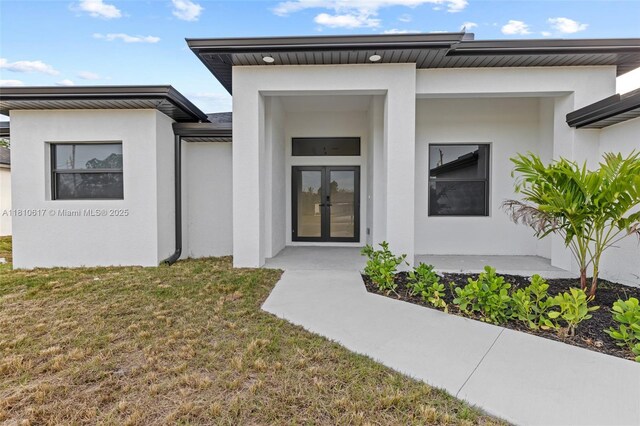 452 Mercedes Ct, Lehigh Acres, FL 33972 - view of exterior entry featuring french doors, stucco siding, and a lawn