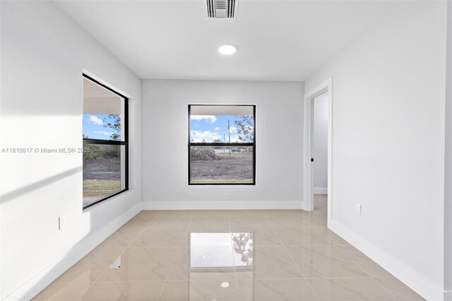 452 Mercedes Ct, Lehigh Acres, FL 33972 - empty room featuring plenty of natural light, light marble finish flooring, and baseboards