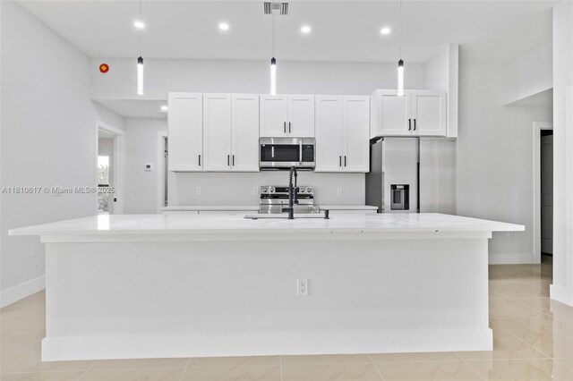 452 Mercedes Ct, Lehigh Acres, FL 33972 - kitchen with stainless steel appliances, a large island with sink, white cabinets, baseboards, and a sink