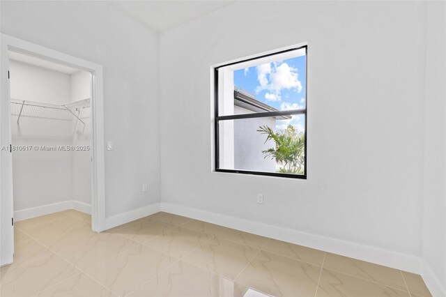452 Mercedes Ct, Lehigh Acres, FL 33972 - unfurnished bedroom with baseboards, light marble finish floors, and a walk in closet