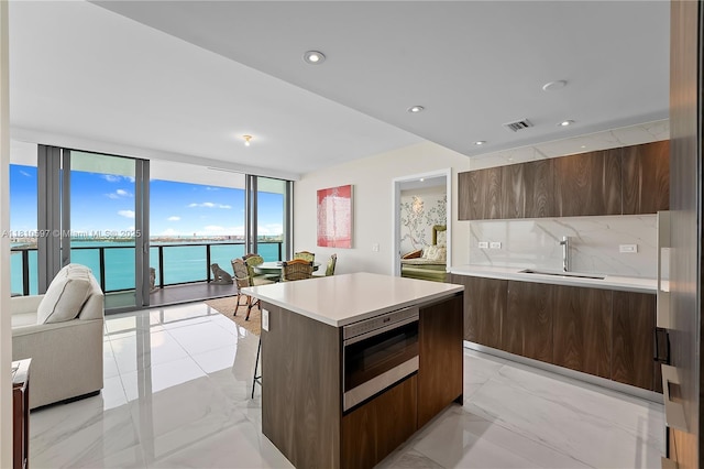 3131 NE 7th Ave Unit 3106, Miami, FL 33137 - kitchen with modern cabinets, a sink, stainless steel microwave, light countertops, and floor to ceiling windows