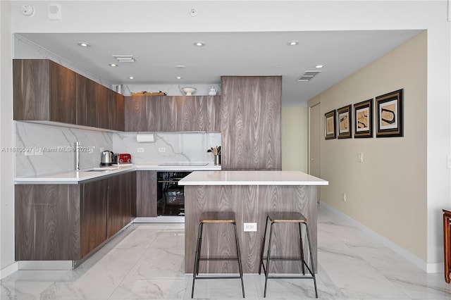 3131 NE 7th Ave Unit 3106, Miami, FL 33137 - kitchen featuring modern cabinets, light marble finish floors, oven, a kitchen island, and recessed lighting