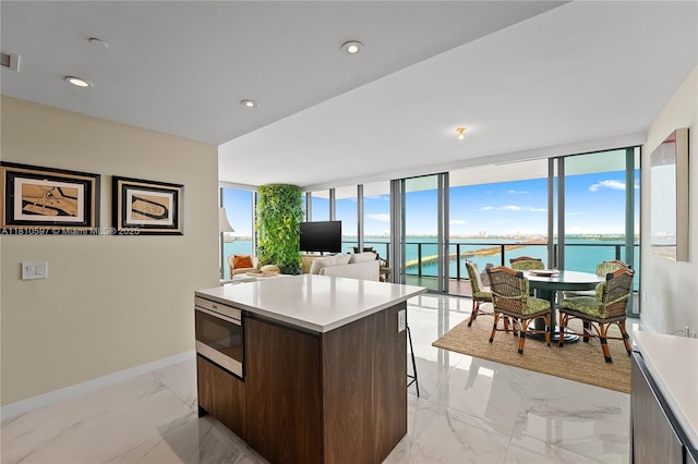 3131 NE 7th Ave Unit 3106, Miami, FL 33137 - kitchen featuring modern cabinets, a center island, light countertops, light marble finish flooring, and baseboards