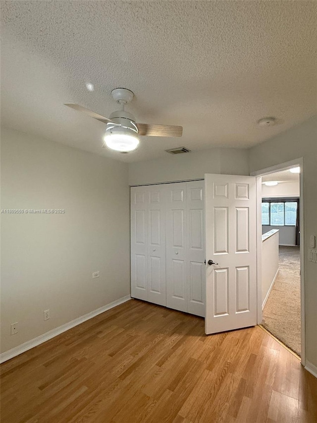 5552 NW 125th Ter, Coral Springs, FL 33076 - unfurnished bedroom featuring a textured ceiling, light wood-style flooring, baseboards, a closet, and a ceiling fan