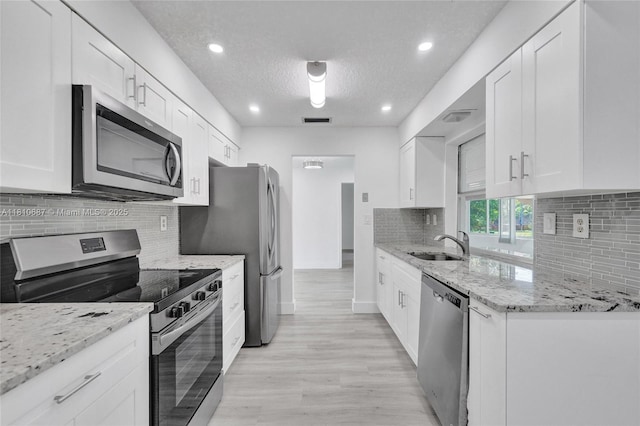 7204 NW 76th Dr, Tamarac, FL 33321 - kitchen with stainless steel appliances, white cabinets, recessed lighting, light wood-type flooring, and light stone countertops