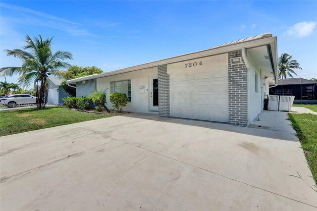 7204 NW 76th Dr, Tamarac, FL 33321 - single story home featuring concrete driveway, brick siding, a garage, and a front yard