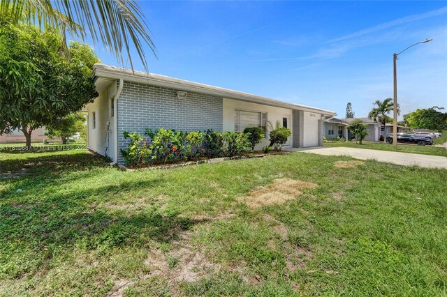 7204 NW 76th Dr, Tamarac, FL 33321 - ranch-style home with concrete driveway, a front yard, a garage, and brick siding