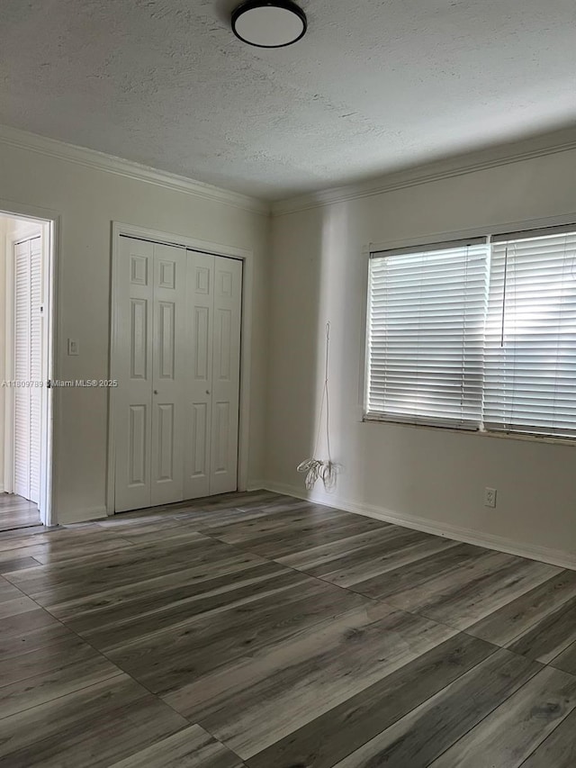 915 N 19th Ave, Hollywood, FL 33020 - unfurnished bedroom with a textured ceiling, ornamental molding, a closet, wood finished floors, and baseboards