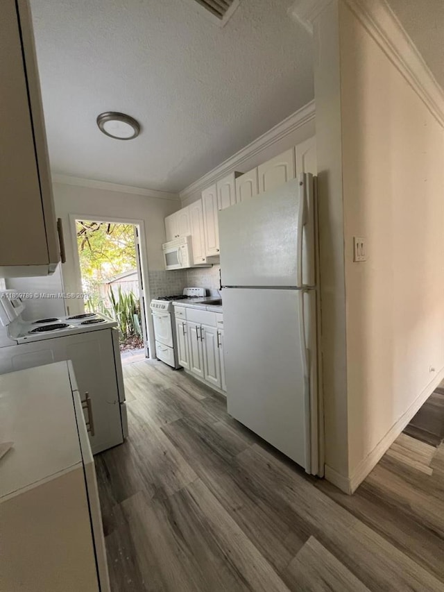 915 N 19th Ave, Hollywood, FL 33020 - kitchen featuring white appliances, ornamental molding, dark wood-style flooring, white cabinets, and washing machine and dryer
