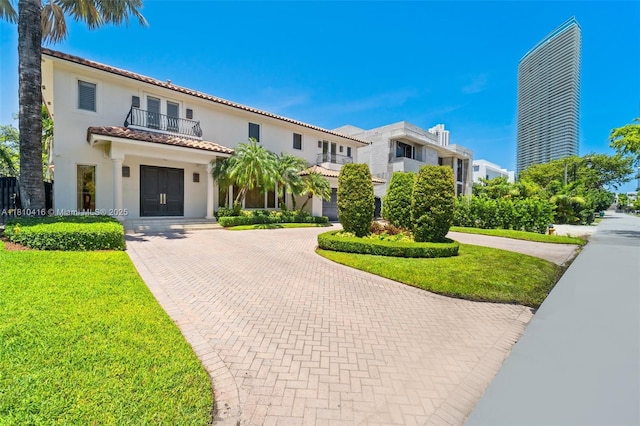 275 189th Ter, Sunny Isles Beach, FL 33160 - mediterranean / spanish house with a balcony, curved driveway, stucco siding, a tiled roof, and a front yard
