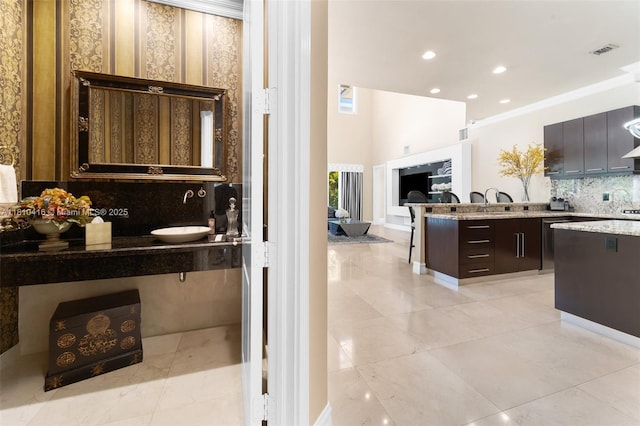 275 189th Ter, Sunny Isles Beach, FL 33160 - kitchen featuring a sink, decorative backsplash, dark brown cabinetry, crown molding, and light stone countertops