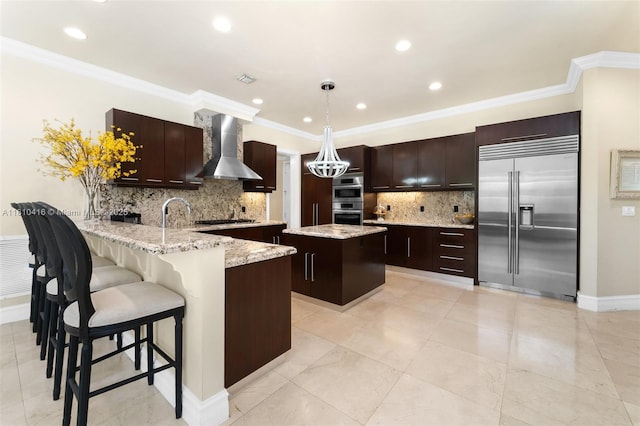 275 189th Ter, Sunny Isles Beach, FL 33160 - kitchen with appliances with stainless steel finishes, wall chimney range hood, a peninsula, dark brown cabinetry, and crown molding