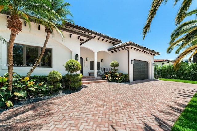 1210 95th St, Bay Harbor Islands, FL 33154 - mediterranean / spanish-style home with decorative driveway, a garage, stucco siding, and covered porch