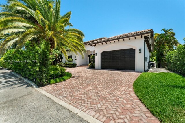 1210 95th St, Bay Harbor Islands, FL 33154 - mediterranean / spanish-style home with a garage, decorative driveway, stucco siding, and a tiled roof
