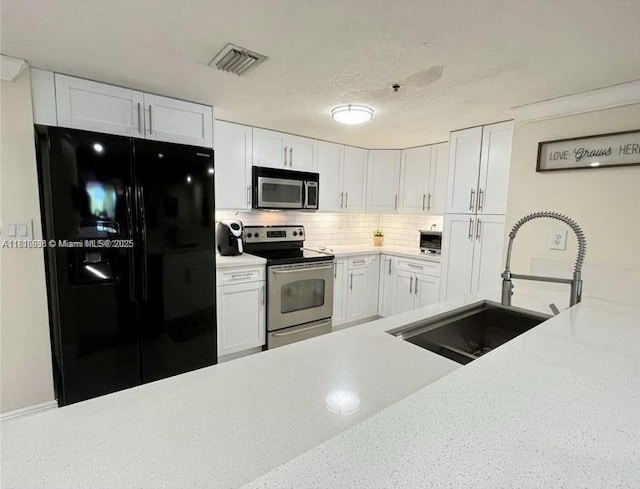 1650 Coral Way Unit 403, Miami, FL 33145 - kitchen featuring stainless steel appliances, a sink, light countertops, white cabinetry, and tasteful backsplash