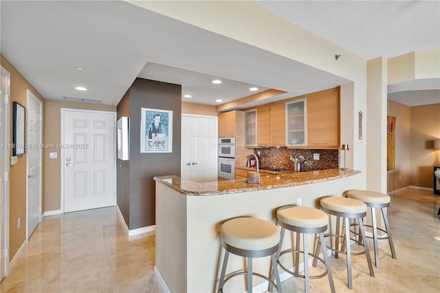 1819 SE 17th St Unit 1501, Fort Lauderdale, FL 33316 - kitchen with stainless steel double oven, a peninsula, light stone countertops, glass insert cabinets, and a kitchen breakfast bar