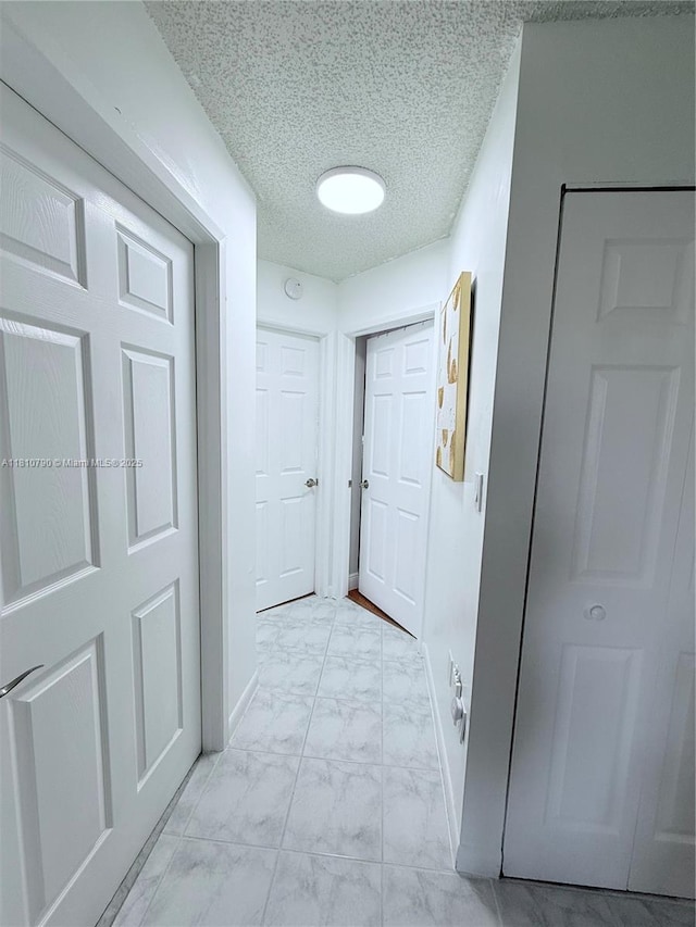 15741 SW 137th Ave Unit 206, Miami, FL 33177 - hallway featuring light marble finish flooring, baseboards, and a textured ceiling