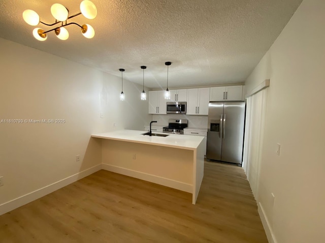 120 Heritage Way, West Palm Beach, FL 33407 - kitchen featuring stainless steel appliances, light wood-style flooring, a peninsula, a sink, and baseboards
