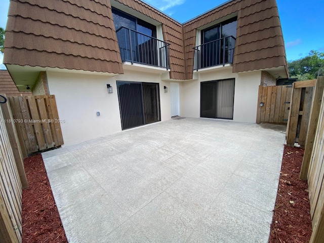 120 Heritage Way, West Palm Beach, FL 33407 - back of property featuring mansard roof, stucco siding, a balcony, a patio area, and a tiled roof