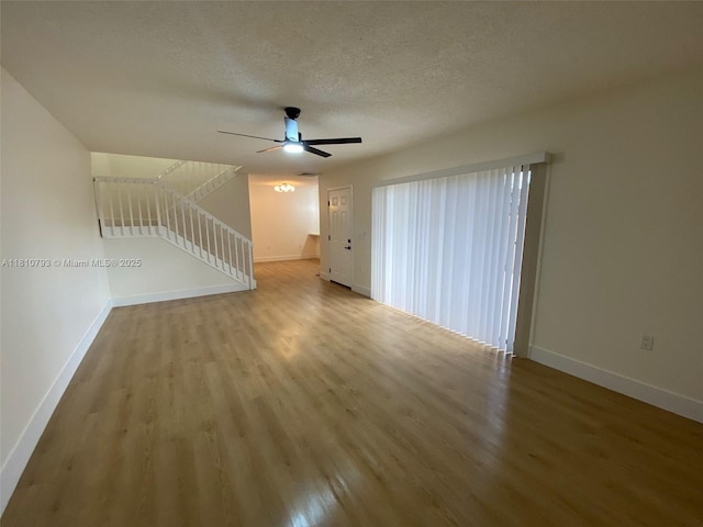 120 Heritage Way, West Palm Beach, FL 33407 - unfurnished living room featuring wood finished floors, baseboards, ceiling fan, and a textured ceiling