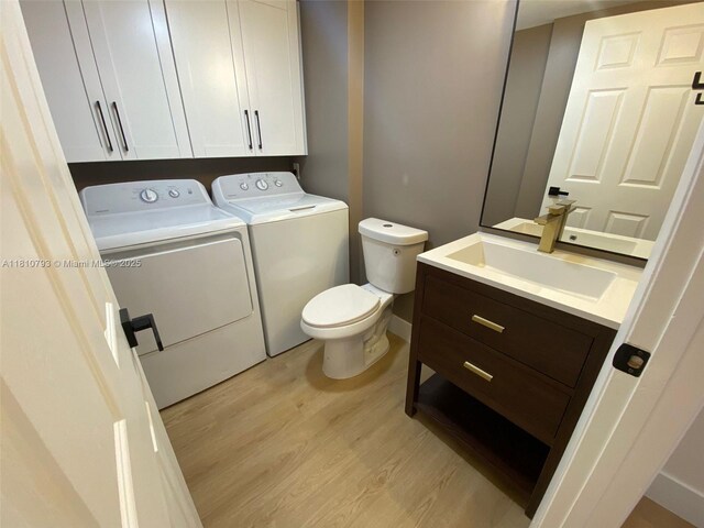 120 Heritage Way, West Palm Beach, FL 33407 - bathroom featuring independent washer and dryer, wood finished floors, vanity, toilet, and baseboards