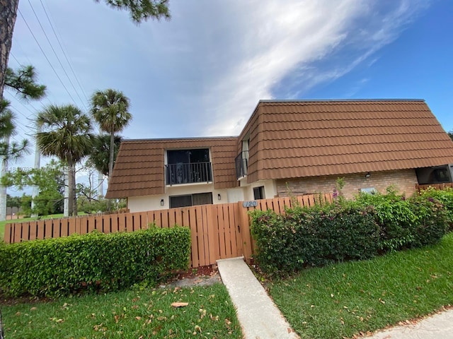 120 Heritage Way, West Palm Beach, FL 33407 - view of front property featuring mansard roof, a fenced front yard, brick siding, and a tiled roof