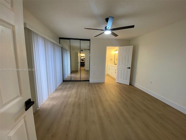 120 Heritage Way, West Palm Beach, FL 33407 - unfurnished bedroom with light wood finished floors, baseboards, a closet, a ceiling fan, and ensuite bath