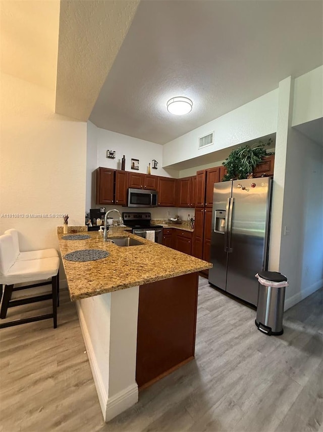 3340 Palomino Dr Unit 211-2, Davie, FL 33024 - kitchen featuring stainless steel appliances, a peninsula, a sink, a textured ceiling, and light wood finished floors