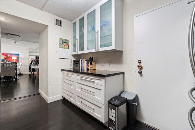 500 Three Islands Blvd Unit 1112, Hallandale Beach, FL 33009 - kitchen with glass insert cabinets, white cabinets, dark countertops, dark wood-style floors, and baseboards
