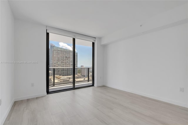 45 SW 9th St Unit 2105, Miami, FL 33130 - empty room featuring expansive windows, baseboards, light wood-style flooring, and a city view