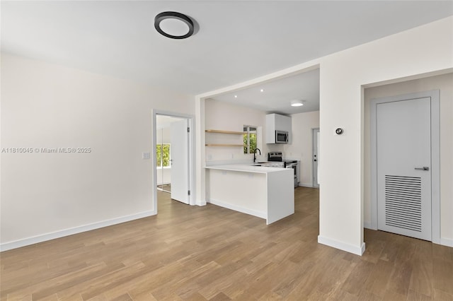 266 NW 42nd St, Miami, FL 33127 - kitchen featuring appliances with stainless steel finishes, a sink, open shelves, light countertops, and light wood-type flooring