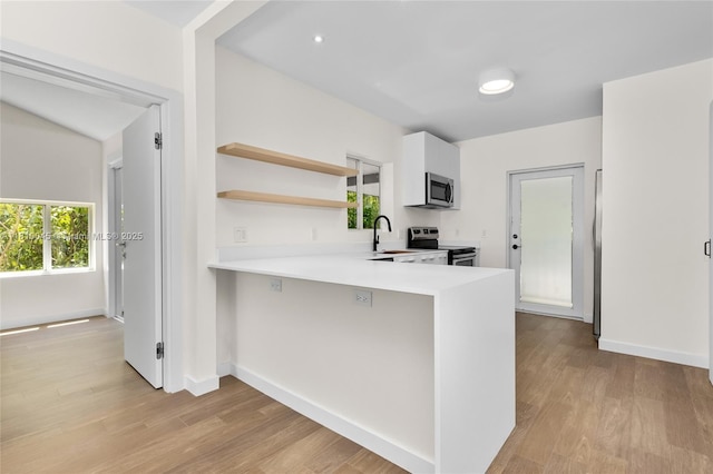 266 NW 42nd St, Miami, FL 33127 - kitchen featuring stainless steel appliances, open shelves, light countertops, and light wood-style flooring