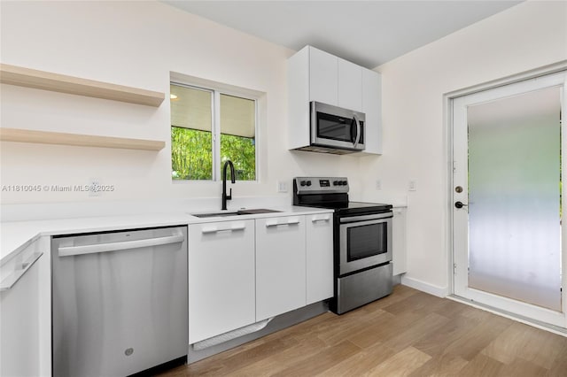 266 NW 42nd St, Miami, FL 33127 - kitchen with stainless steel appliances, a sink, light wood-style floors, white cabinetry, and light countertops