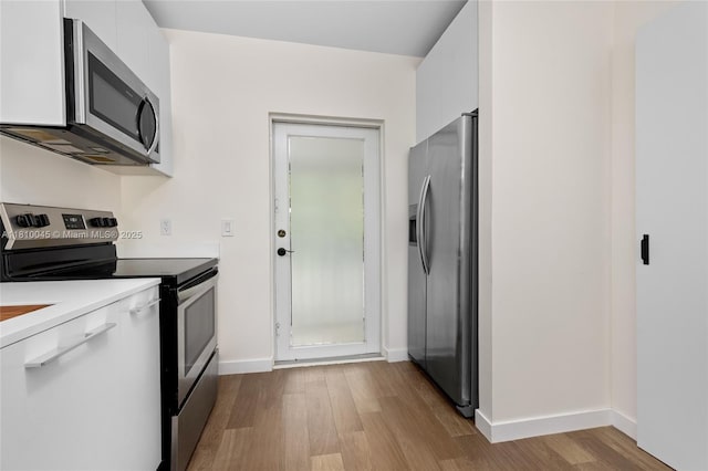 266 NW 42nd St, Miami, FL 33127 - kitchen with appliances with stainless steel finishes, wood finished floors, white cabinets, baseboards, and modern cabinets