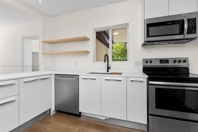 266 NW 42nd St, Miami, FL 33127 - kitchen featuring appliances with stainless steel finishes, a sink, white cabinets, light countertops, and wood finished floors