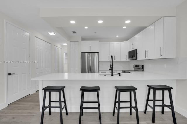 4123 Parkside Dr, Jupiter, FL 33458 - kitchen with appliances with stainless steel finishes, a sink, a peninsula, light wood finished floors, and light countertops