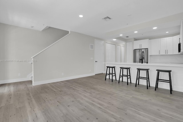 4123 Parkside Dr, Jupiter, FL 33458 - kitchen featuring freestanding refrigerator, recessed lighting, a peninsula, a kitchen bar, and white cabinets
