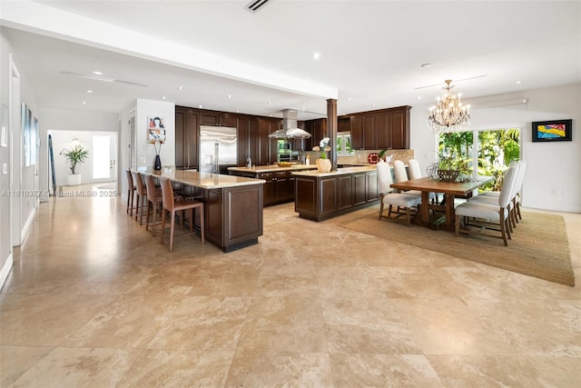 425 N Shore Dr, Miami Beach, FL 33141 - kitchen featuring built in refrigerator, dark brown cabinetry, a kitchen island, light countertops, and a chandelier