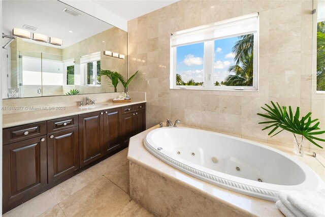 425 N Shore Dr, Miami Beach, FL 33141 - bathroom with vanity, a whirlpool tub, tile walls, plenty of natural light, and tile patterned flooring