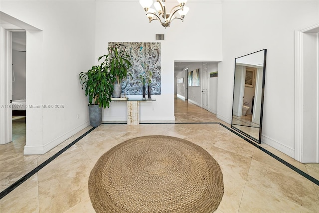 425 N Shore Dr, Miami Beach, FL 33141 - foyer entrance with inlaid floor details, baseboards, a chandelier, and a high ceiling