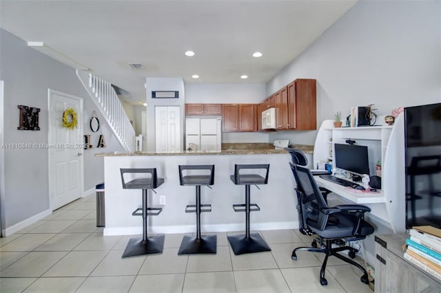 9051 SW 227th St Unit 2, Cutler Bay, FL 33190 - kitchen with white appliances, a peninsula, a breakfast bar, an office area, and brown cabinets