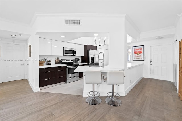 3245 NE 184th St Unit 13402, Aventura, FL 33160 - kitchen with appliances with stainless steel finishes, modern cabinets, ornamental molding, a kitchen breakfast bar, and light countertops