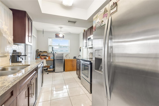 5723 NW 69th Ave, Tamarac, FL 33321 - kitchen featuring appliances with stainless steel finishes, decorative backsplash, light tile patterned flooring, light stone counters, and a ceiling fan