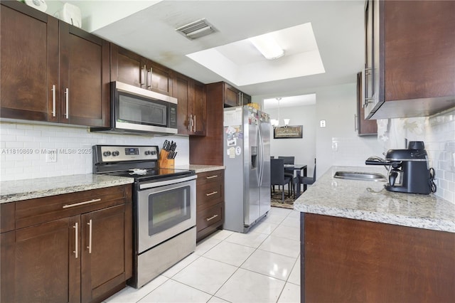 5723 NW 69th Ave, Tamarac, FL 33321 - kitchen featuring appliances with stainless steel finishes, a sink, decorative backsplash, a tray ceiling, and light stone counters