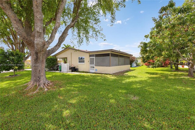 5723 NW 69th Ave, Tamarac, FL 33321 - rear view of property featuring a sunroom, a yard, and stucco siding