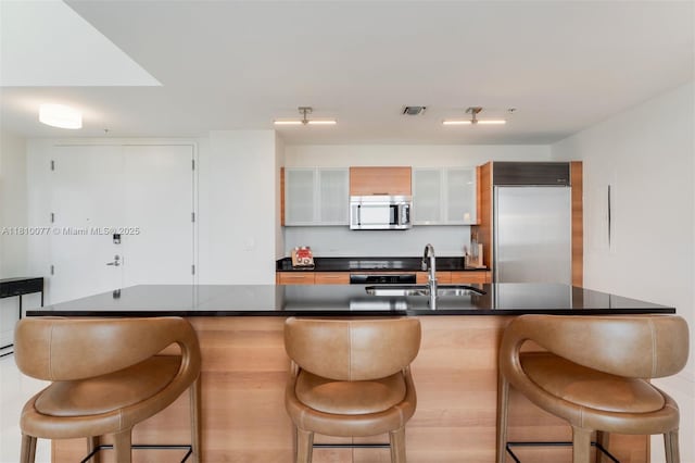 3301 NE 1st Ave Unit Ph7, Miami, FL 33137 - kitchen featuring stainless steel appliances, a sink, a kitchen breakfast bar, dark countertops, and glass insert cabinets