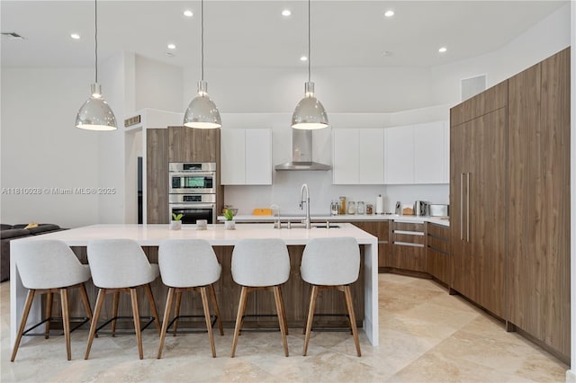 146 Dockside Cir, Weston, FL 33327 - kitchen with modern cabinets, stainless steel double oven, wall chimney range hood, light countertops, and white cabinets