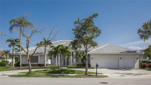 146 Dockside Cir, Weston, FL 33327 - view of front of house featuring french doors, decorative driveway, an attached garage, a tile roof, and stucco siding
