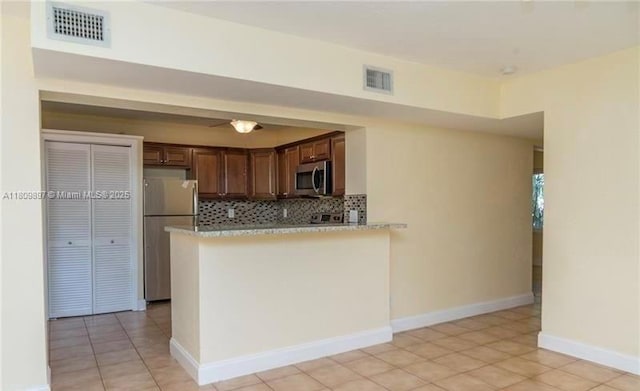 1215-1217 NE 16th Ave, Fort Lauderdale, FL 33304 - kitchen with appliances with stainless steel finishes, tasteful backsplash, light countertops, a peninsula, and light tile patterned floors