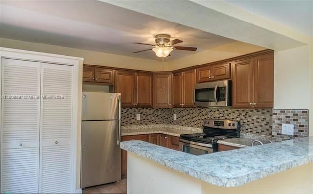 1215-1217 NE 16th Ave, Fort Lauderdale, FL 33304 - kitchen with appliances with stainless steel finishes, a peninsula, ceiling fan, light countertops, and brown cabinetry